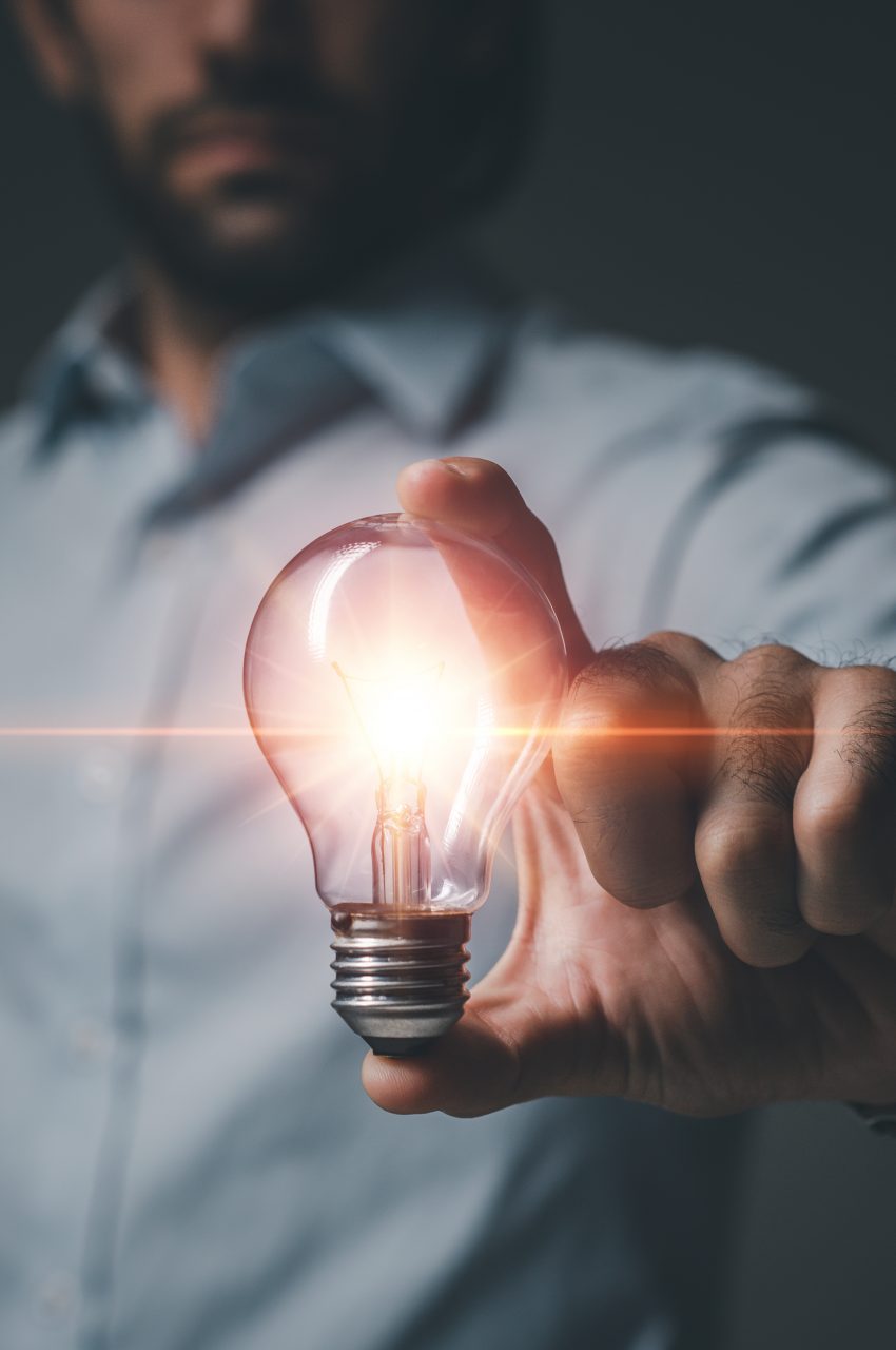 Hand of Man holding light bulb on dark blackground. Idea innovation and creativity concept. Innovative technology and business development